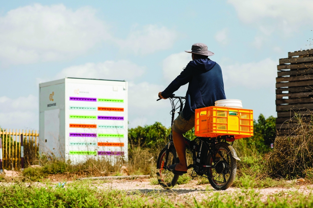 A man cycles next to a robotic beehive, developed by Israeli startup Beewise, in Beit Haemek