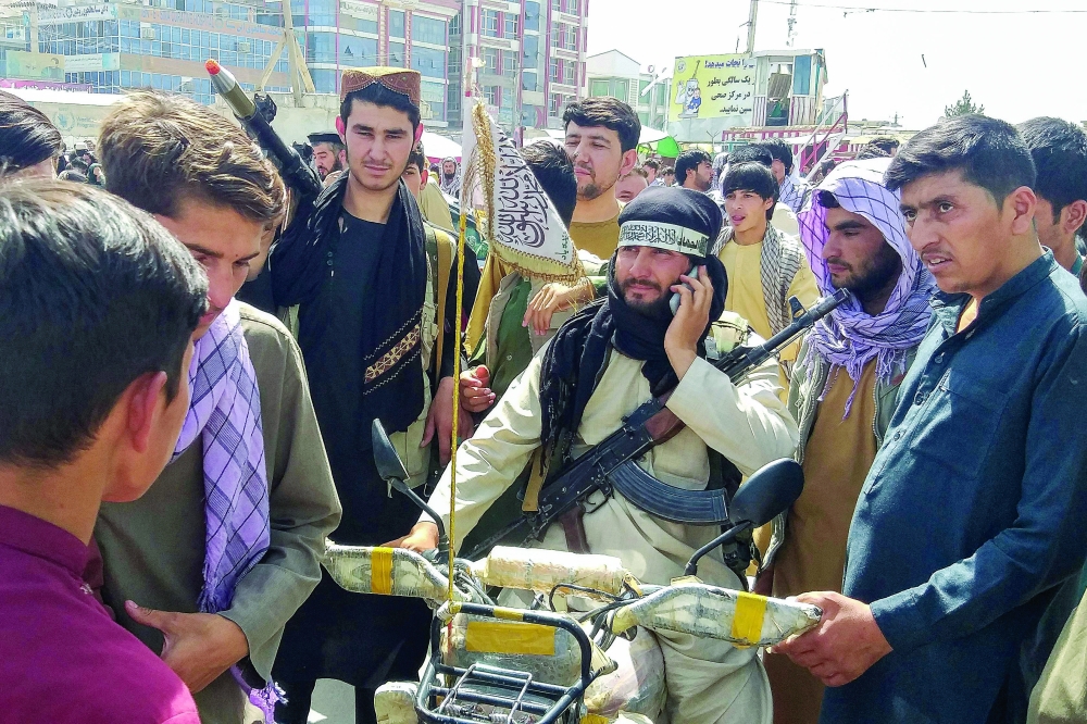 Taliban fighter (C) is seen surrounded by locals at Pul-e-Khumri on Wednesday after Taliban captured the capital of Baghlan province about 200 km north of Kabul. -- AFP
