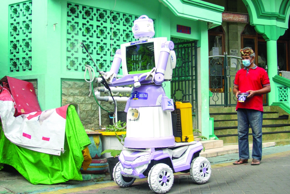 Aseyanto, 53, a resident of the Tembok Gede neighbourhood, operates the "Delta Robot", made from household items like pots, pans and an old television monitor, in Surabaya. -- Reuters