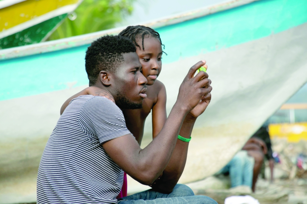 A migrant and his daughter check a photo on his phone as they wait to cross into Panama to continue their journey toward the US, in Necocli, Colombia. -- Reuters