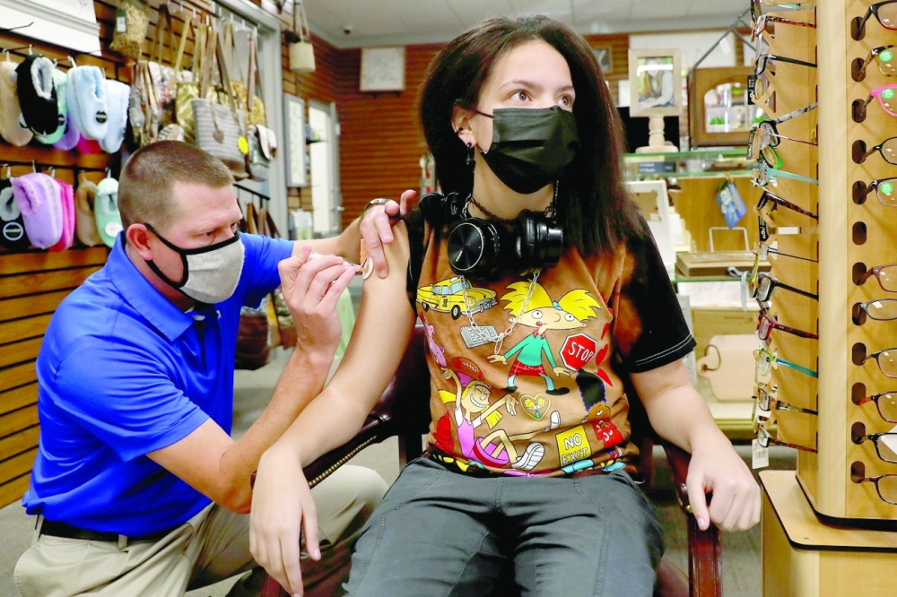 FILE PHOTO: Caitlyn Jendrejas, 15, wears a protective face mask amid the coronavirus disease (COVID-19) pandemic while receiving her second dose of the Pfizer vaccine from pharmacist Shane Dixon at the Watson Pharmacy in Fordyce, Arkansas, U.S., August 12, 2021. REUTERS/Shannon Stapleton/File Photo
