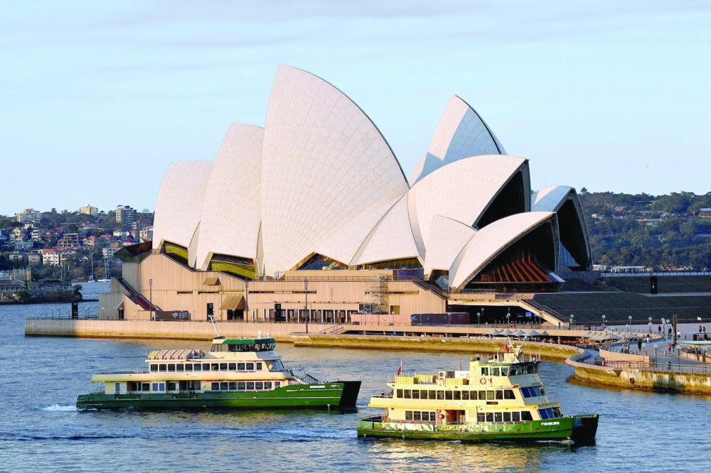 Near-empty ferries pass in front of the Opera House in Sydney on Saturday. -- AFP