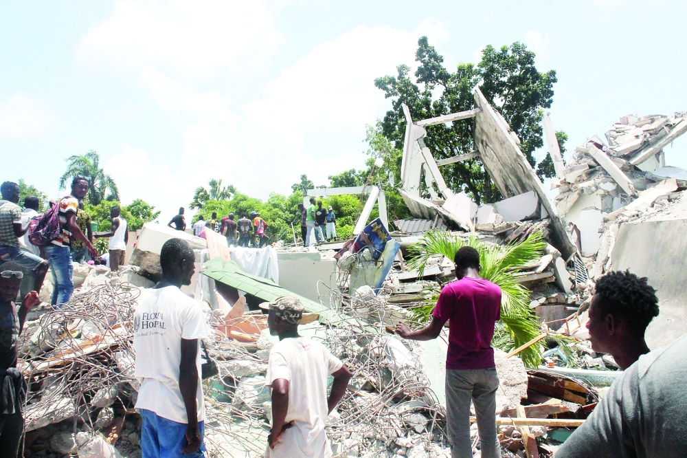 People search through the rubble of what used to be the Manguier Hotel after the earthquake hit on Saturday in Les Cayes, southwest Haiti. -- AFP