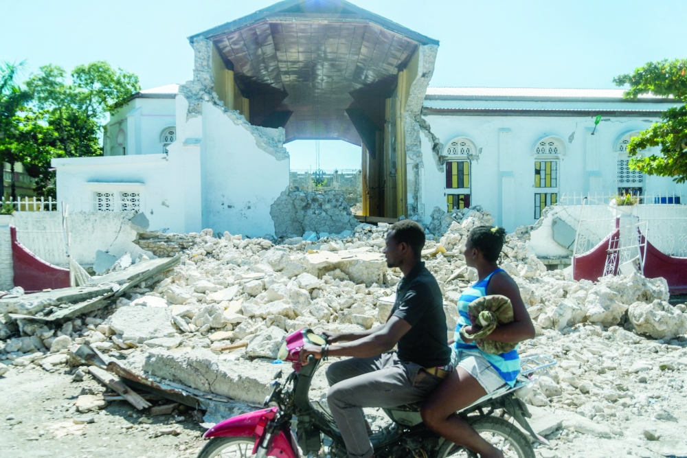 People drive past the remains of the "Sacré coeur des Cayes" church in Les Cayes on Monday. -- AFP