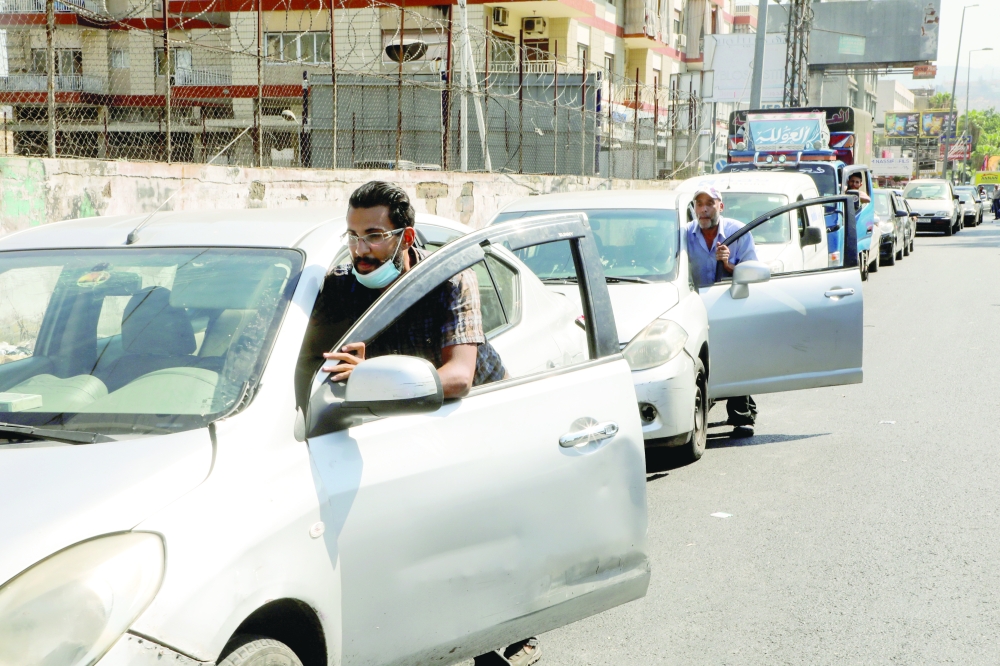 People push their cars due to a lack of fuel, near a gas station in Dora, Lebanon, on Tuesday. -- Reuters