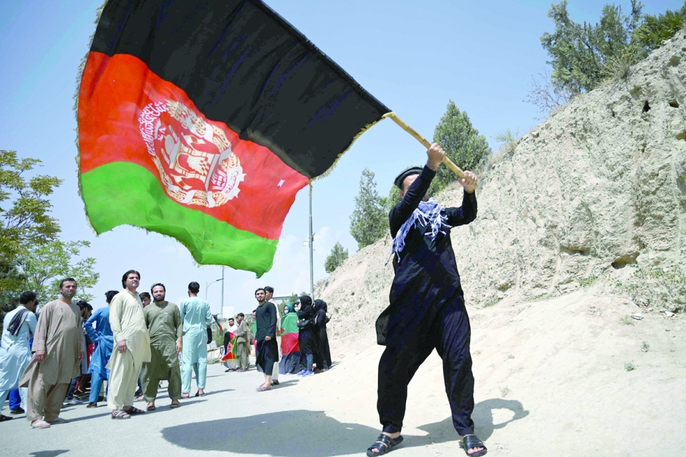 An Afghan waves the national flag as they celebrate the 102th Independence Day of Afghanistan in Kabul. - AFP