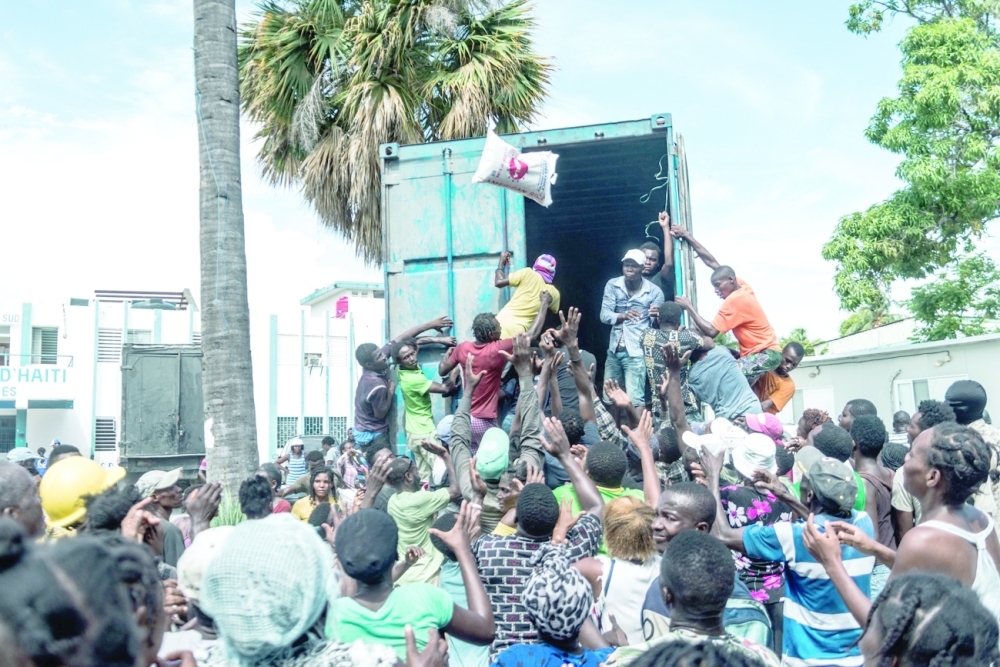 A man throws a bag of rice into a crowd of earthquake victims gathered for the distribution of food and water at the "4 Chemins" crossroads in Les Cayes on Friday. -- AFP