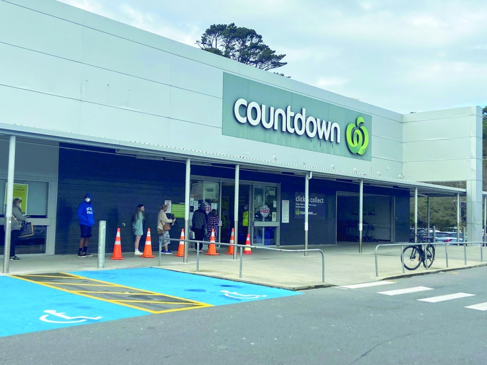 People stand in line outside a grocery store in Wellington. -- Reuters