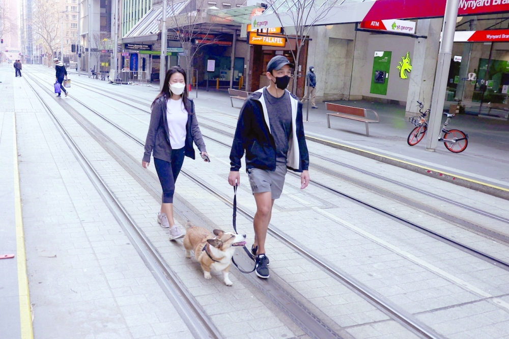 People walking along the quiet George Street in Sydney as the city extended its two-month-old lockdown and introduced a partial curfew to contain a fast-spreading coronavirus outbreak. -- AFP