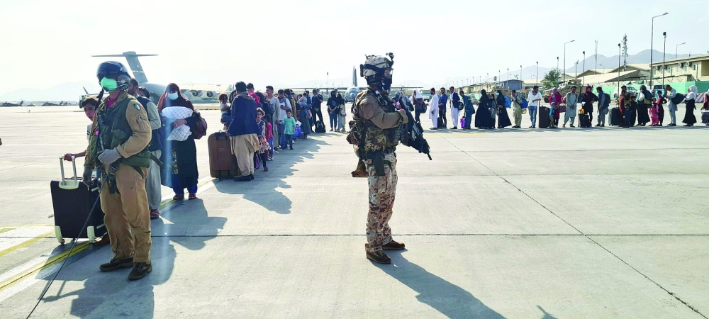 Afghan evacuees queue before boarding Italy's military aircraft during evacuation at Kabul's airport on Sunday. -- Reuters
