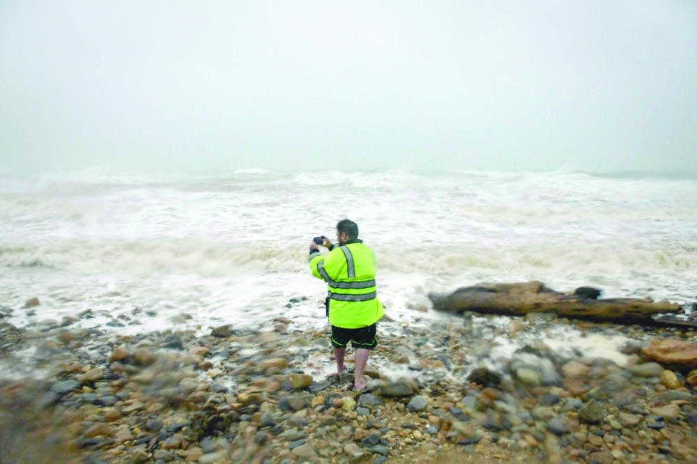 A man takes a photo on a beach as Tropical Storm Henri approaches, in Montauk, Long Island on Sunday. -- AFP