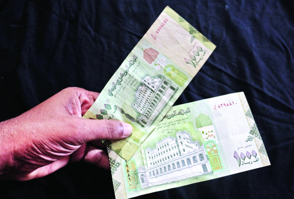 A man holds (bottom to top) new and older issues of the 1000 Yemeni Riyal banknote in Aden. -- AFP
