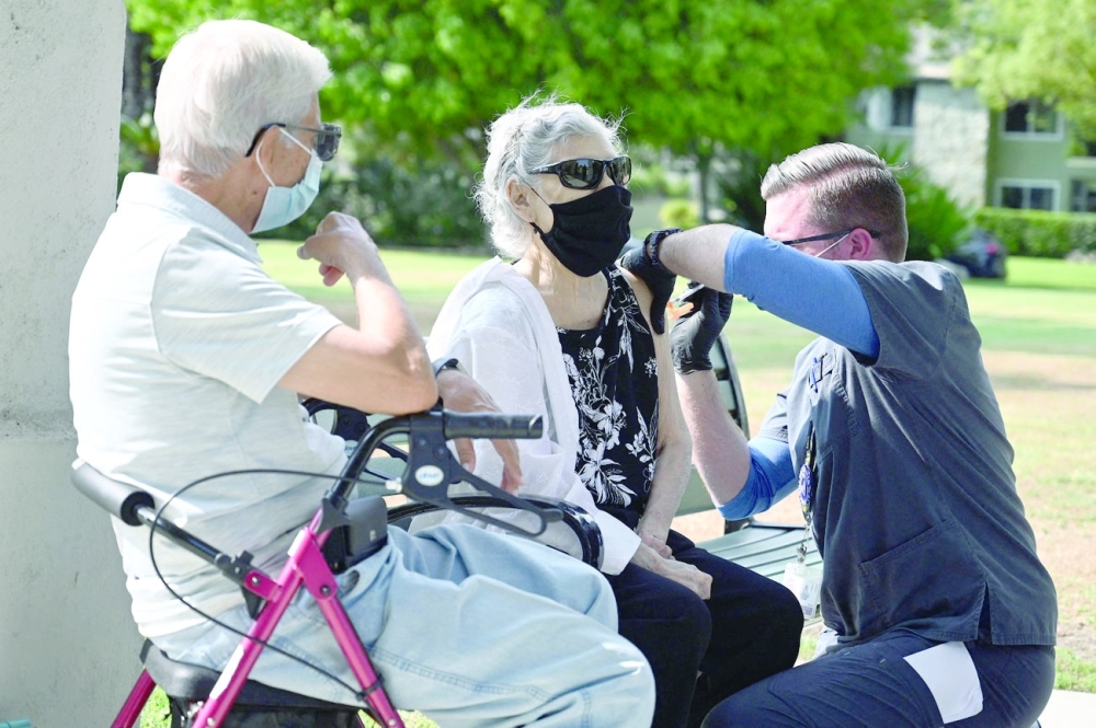 Nurse Kevin Grellman administers a third booster dose of Pfizer Covid-19 vaccine to Armida Gomez, 81, as her husband Jose Gomez, 80, waits for his turn during a vaccination clinic in California. -- AFP 