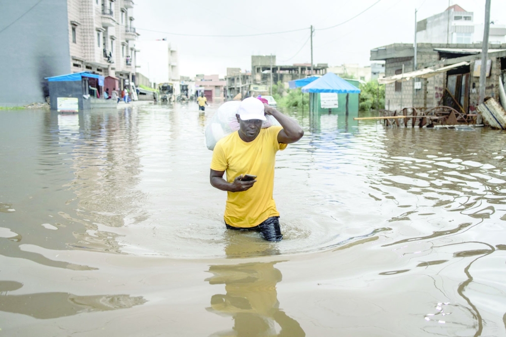 A man carries his belongings out of his house in the flooded neighbourhood of Keur Massar, Dakar. AFP file photo
