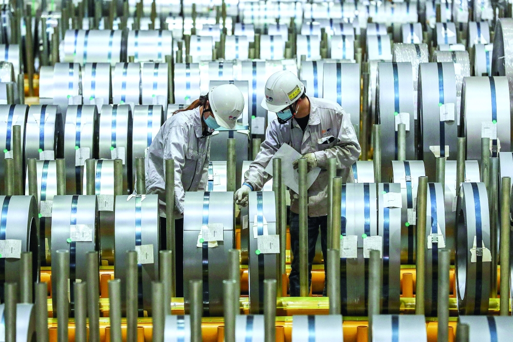 Workers checking rolls of sheet aluminium at a factory in Wuhan, central Hubei province, China. — AFP