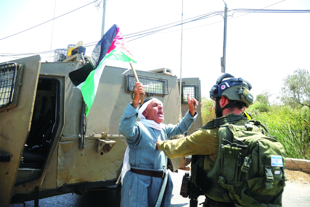 A demonstrator waves a Palestine's flag during a protest against Israeli settlements, in Beita, in the Israeli-occupied West Bank on Wednesday. -- Reuters