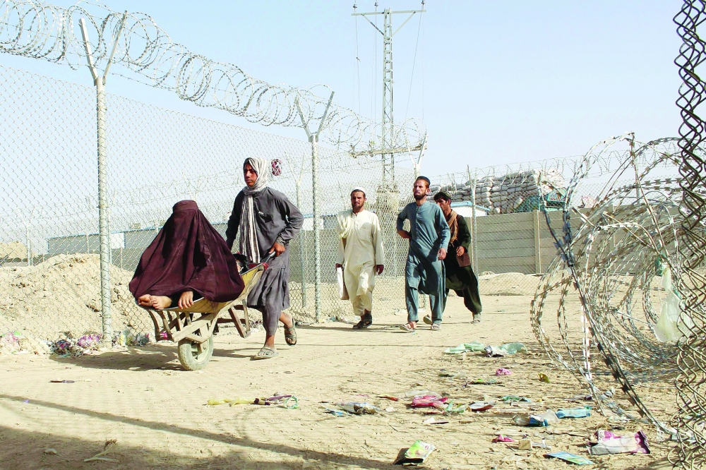Afghans walk along a fenced corridor after crossing into Pakistan following the Taliban's stunning military takeover of Afghanistan. -- AFP