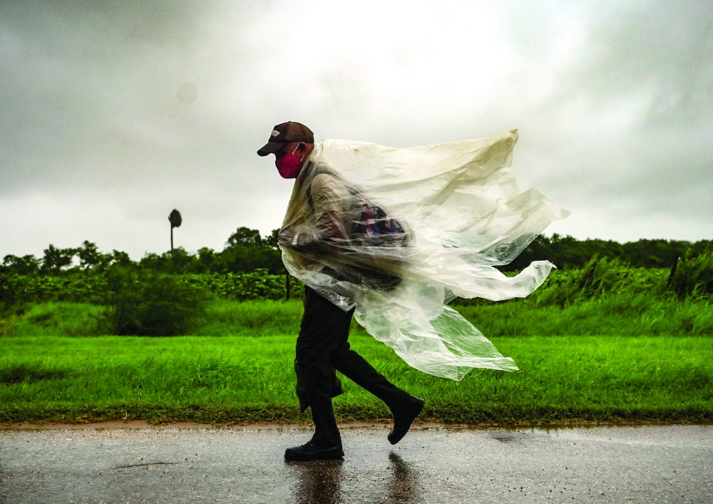 A man walks under the rain in Batabano, Mayabeque province, about 60 km south of Havana, on Saturday. -- AFP
