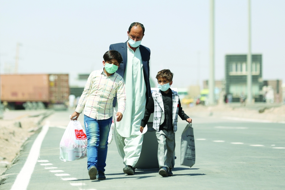 Afghan nationals walk at the Dowqarun border crossing between Iran and Afghanistan, Razavi Khorasan Province, Iran, on Sunday. - Reuters