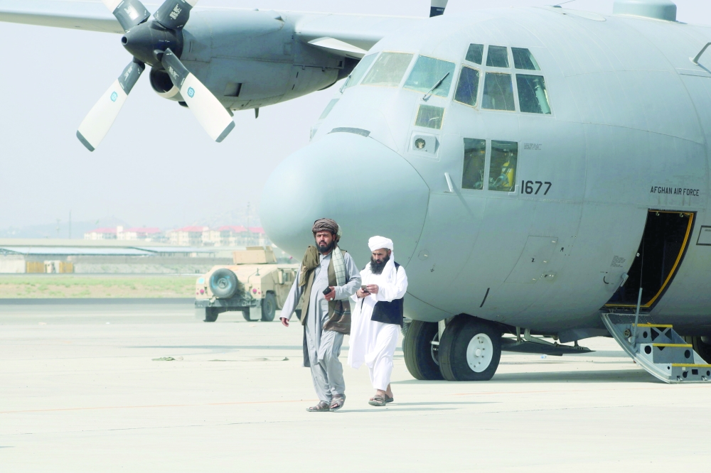 Taliban walk in front of a military airplane a day after the US troops withdrawal from Hamid Karzai International Airport in Kabul, Afghanistan, on Tuesday. - Reuters