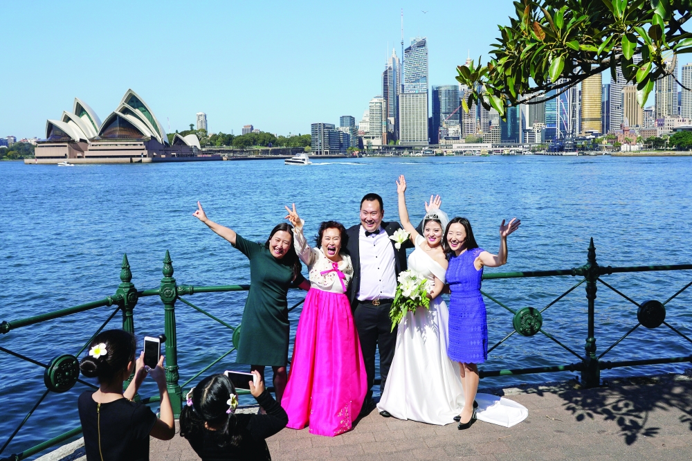 Groom Daniel Kim and bride Ella Kim pose for pictures with loved ones just after being married on the first day of eased restrictions in Sydney, Australia, on Friday. - Reuters