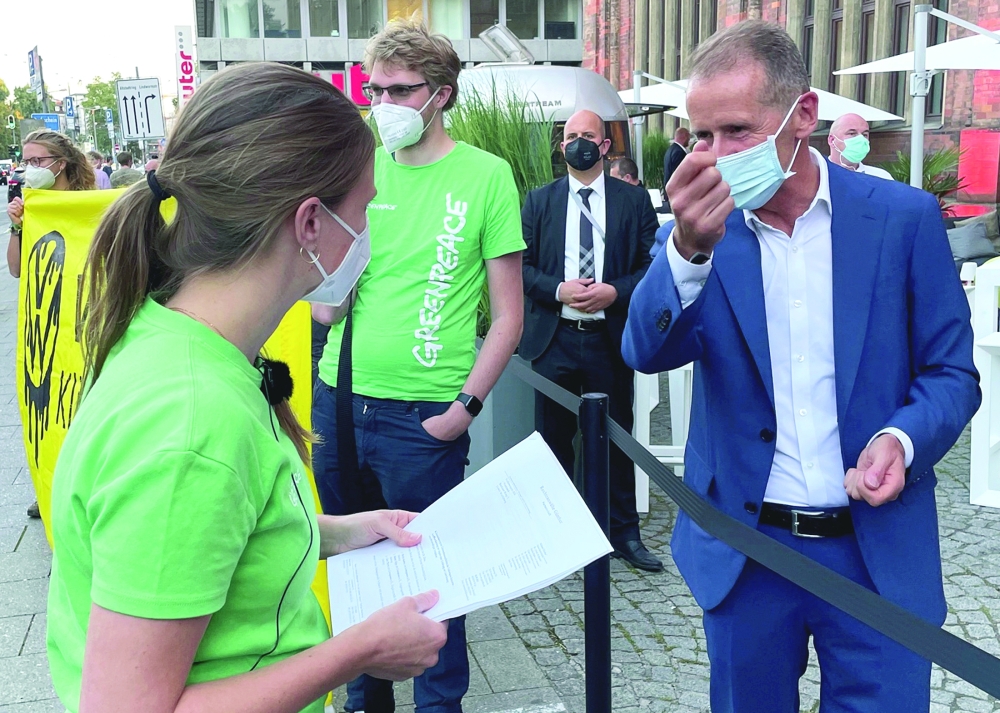 Herbert Diess, CEO of German carmaker Volkswagen AG talks to members of Greenpeace ahead of the Munich Motor Show IAA Mobility 2021, in Munich. - Reuters