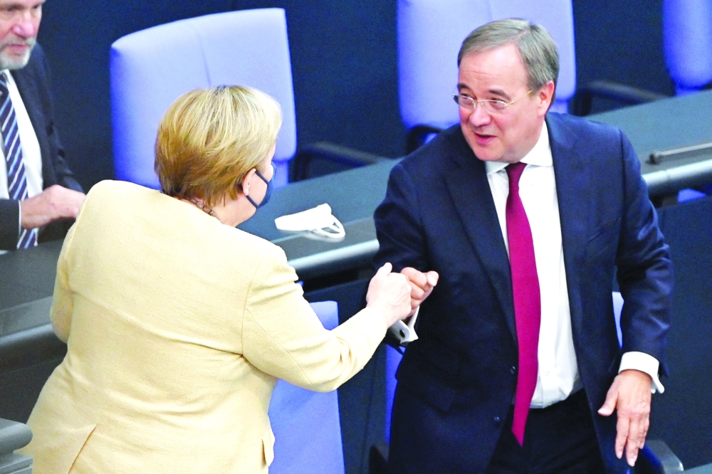 German Chancellor Angela Merkel bumps fists with North Rhine-Westphalia's State Premier and CDU chancellor candidate Armin Laschet during a session at the Bundestag. - AFP

