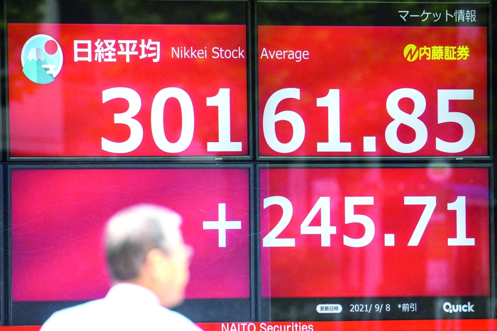 A pedestrian stands in front of a stock indicator displaying numbers of the 225-issue Nikkei Stock Average climbed 245.71 points in Tokyo. -  AFP

