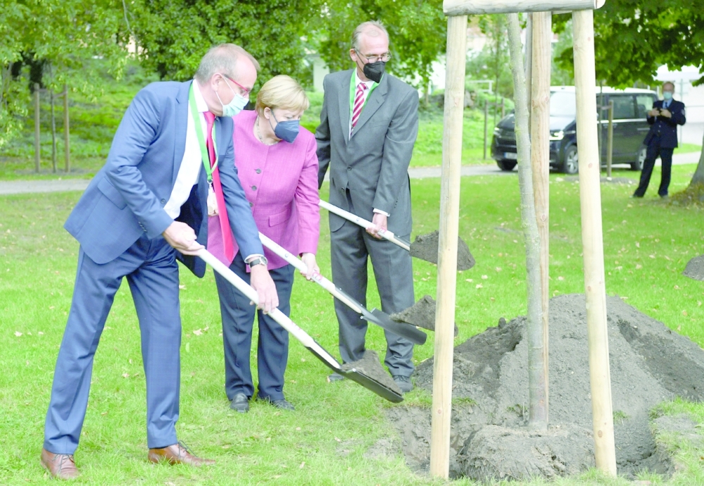 German Chancellor Angela Merkel, The Major of Templin Detlef Tabbert and Franz-Christoph Michel take part in a tree planting event during the 750th city anniversary celebrations in Burgergarten, in Templin. -- Reuters