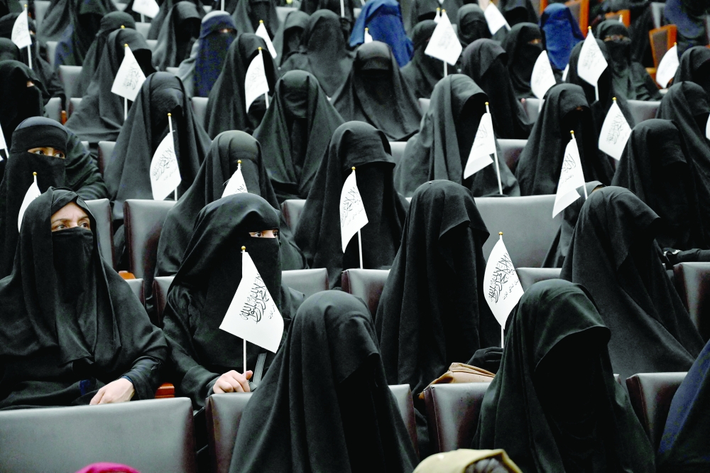 Students hold Taliban flags as they listen women speakers before a pro-Taliban rally at the Shaheed Rabbani Education University in Kabul on Saturday. -- AFP