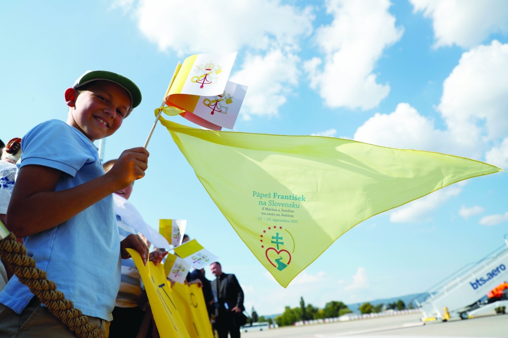 A boy holds Vatican City flags as he waits for Pope Francis to arrive at Bratislava International Airport, Slovakia. - Reuters