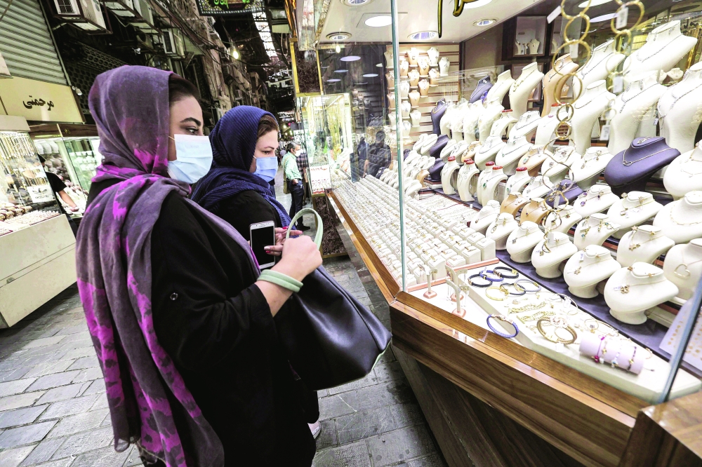 Customers view items behind the glass window of a jewellery shop at Tehran's Grand Bazaar. -- AFP 