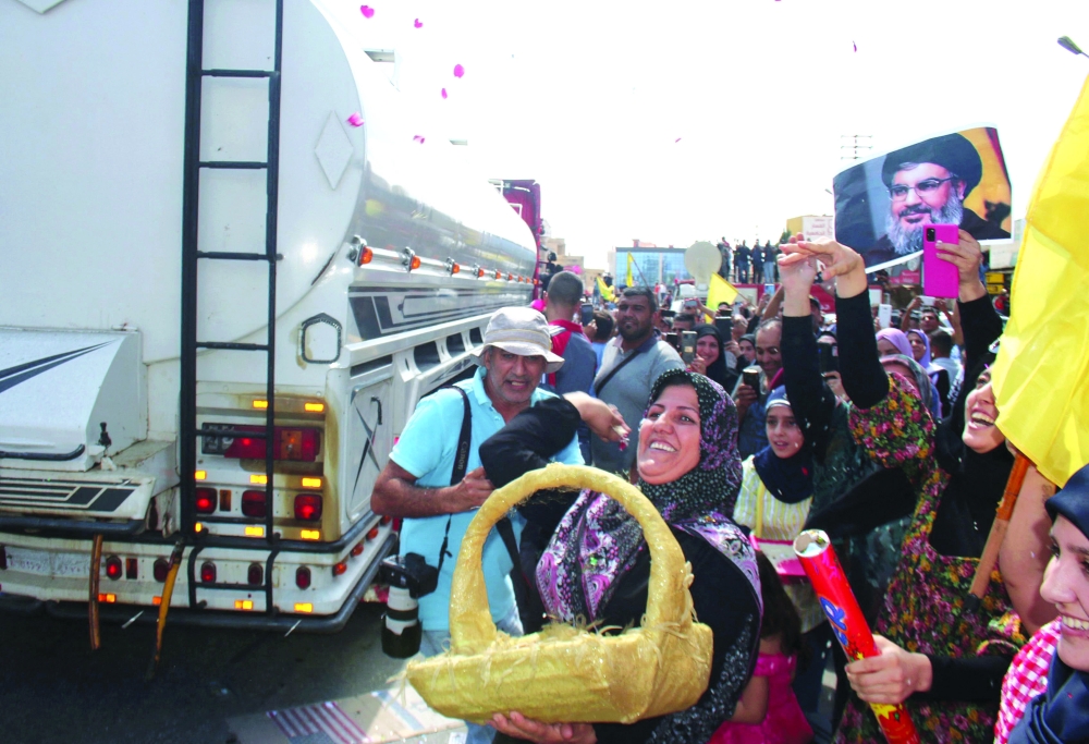 A woman tosses rose petals as people gather to welcome tankers carrying Iranian fuel, upon their arrival from Syria in the city of Baalbeck, in Lebanon's Bekaa valley, on Thursday. -- AFP