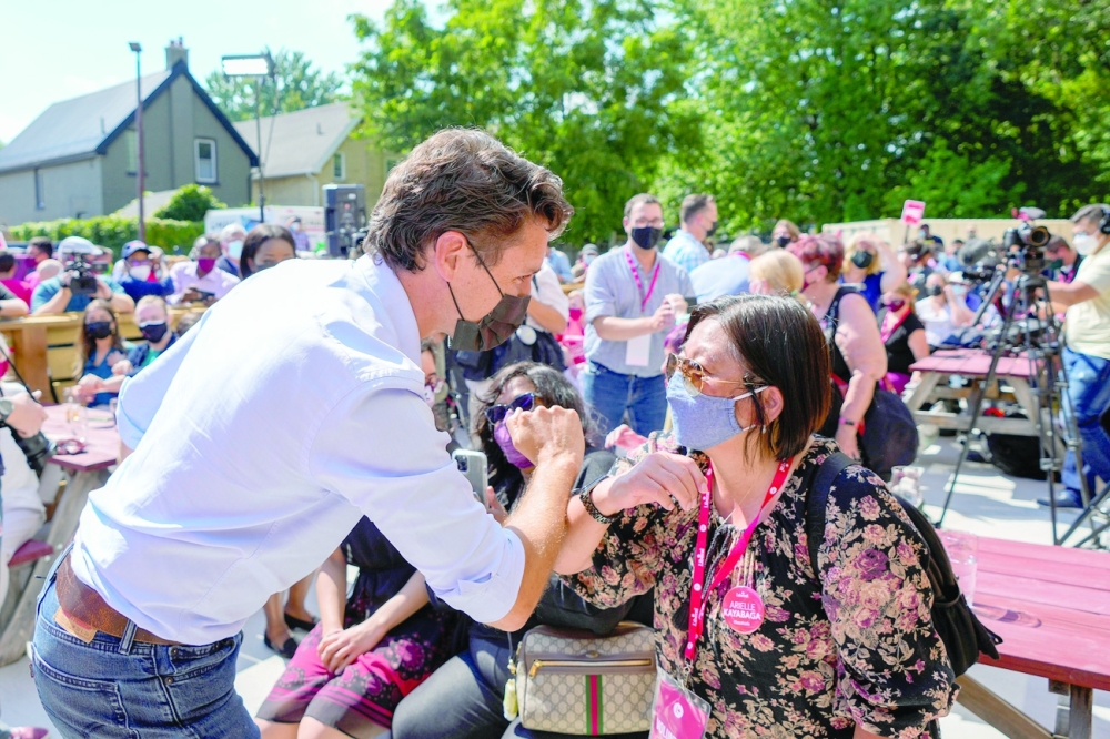 Canada's Liberal Prime Minister Justin Trudeau elbow bumps a person during an election campaign stop in Ontario. -- Reuters