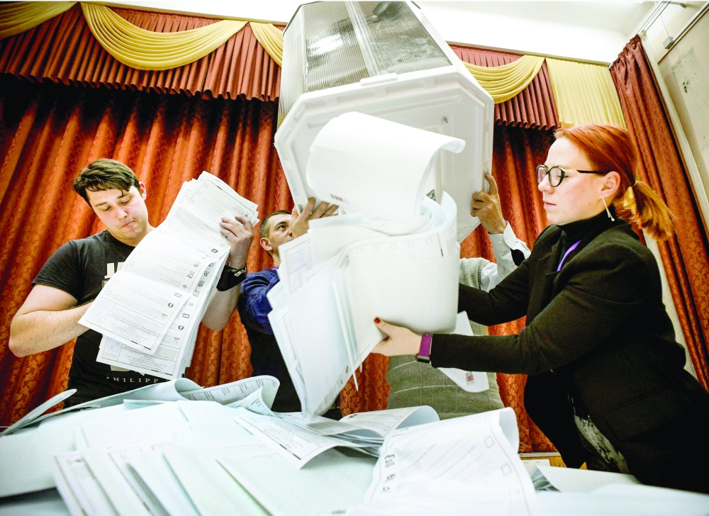 Members of a local electoral commission empty a ballot box at a polling station after the last day of the three-day parliamentary election in Moscow. - AFP