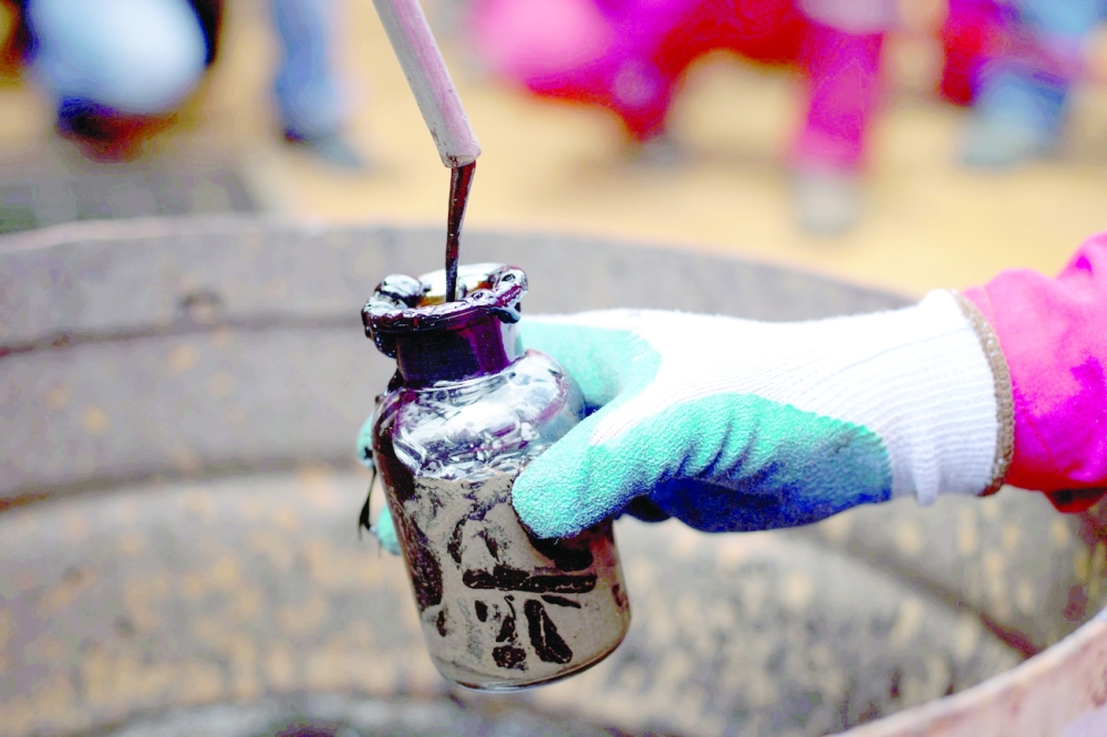 FILE PHOTO: A worker collects a crude oil sample at an oil well operated by Venezuela's state oil company PDVSA in Morichal
