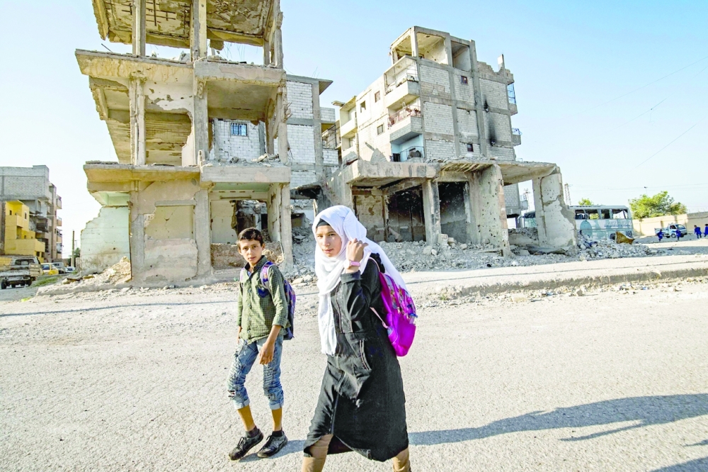 Syrian students walk to school past damaged buildings in the northern city of Raqqa. -- AFP