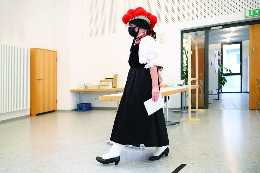 A woman wearing a traditional 'Bollenhut' pompon hat typical for the Black Forest region arrives to vote for the German federal elections at a polling station in southwestern Germany. - AFP


