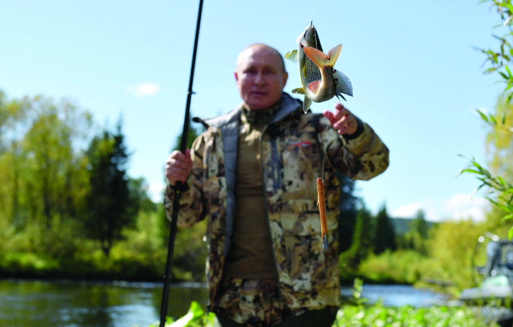 Russian President Vladimir Putin poses with a fish in the taiga. - AFP

