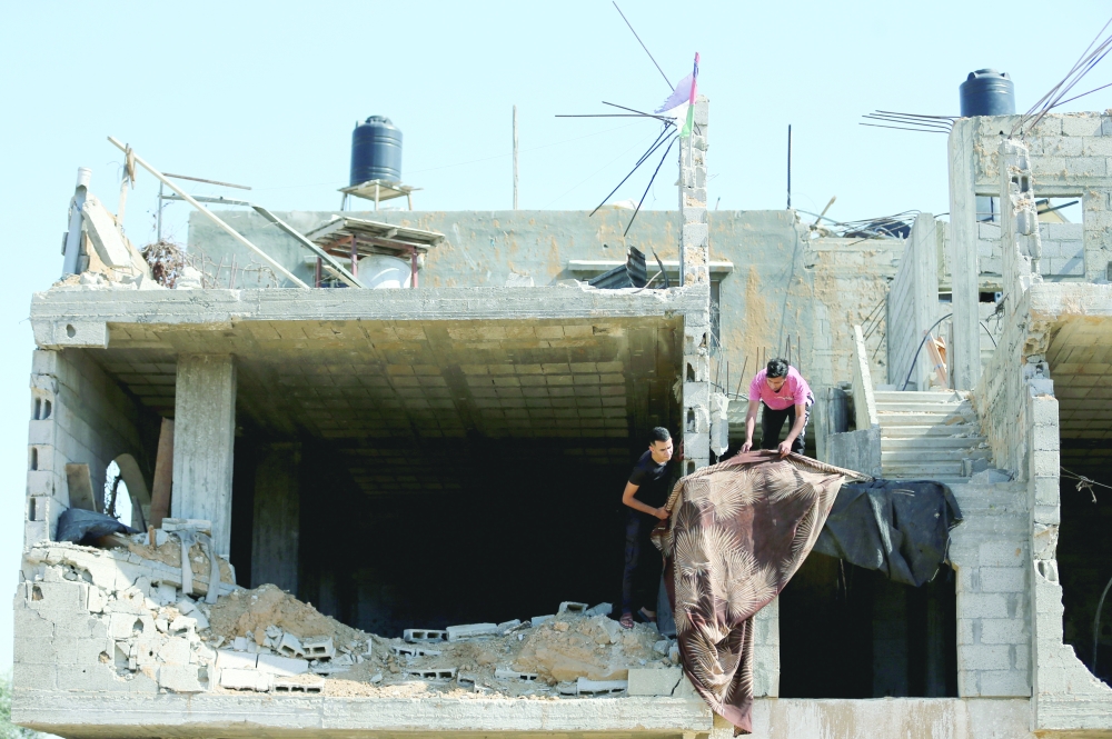 Palestinians work in their house that was destroyed by Israeli strikes during Israel-Hamas fighting last May, in Khan Younis in southern Gaza Strip, on Sunday. - Reuters