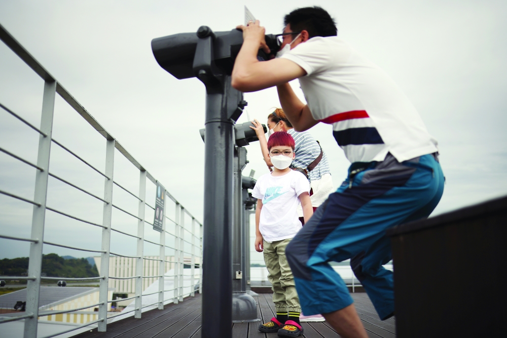 A boy stands in between his parents as they look towards the north through a pair of binoculars near the demilitarized zone separating the two Koreas in Paju, South Korea, on Tuesday. - Reuters
