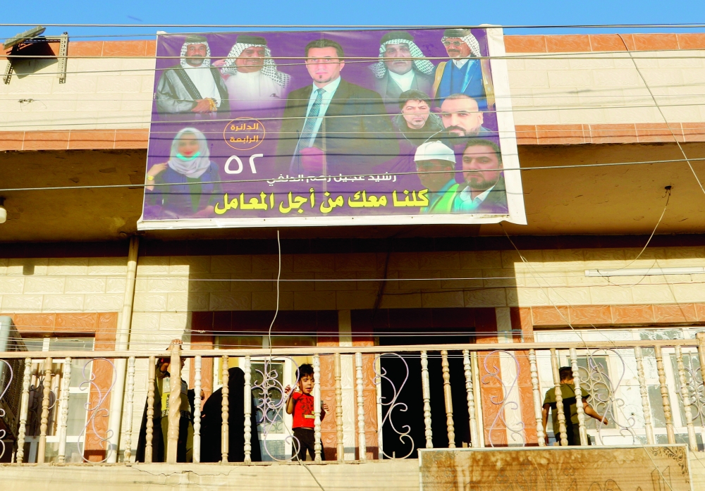 A child is pictured from an apartment building with an election campaign poster ahead of the parliamentary election, in Baghdad, Iraq. - Reuters