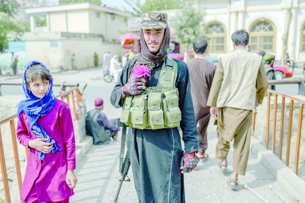 A Taliban fighter poses for a picture holding a flower in Kabul on Friday. -- AFP
