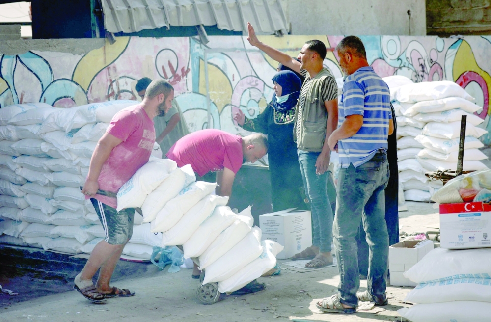 A Palestinian volunteer pushes a trolley of food rations outside an aid distribution center run by the United Nations Relief and Works Agency (UNRWA) at the Al Shati camp for Palestinian refugees in Gaza City.  -- AFP
