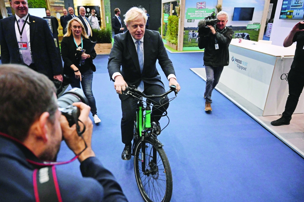 Britain's Prime Minister Boris Johnson rides an e-Bike on the third day of the annual Conservative Party Conference in Manchester, northwest England. - AFP

