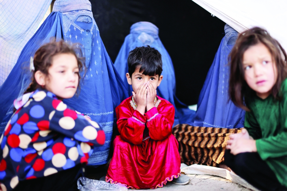 Afghan girls and women, who are among displaced families, sit in front of a tent at a makeshift shelter at Shahr-e Naw park, in Kabul. - Reuters