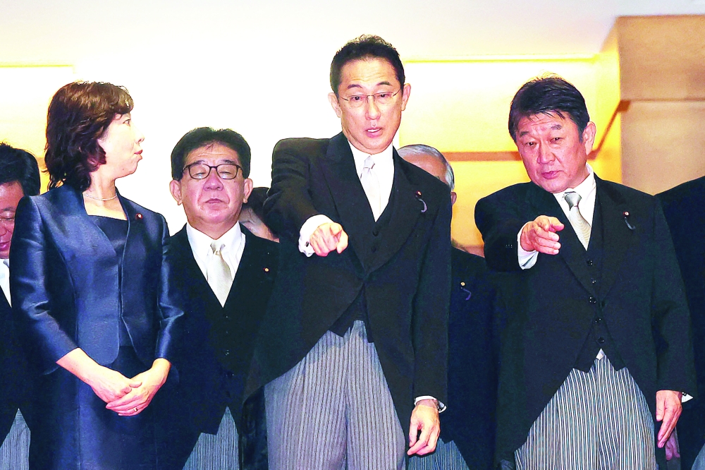 Japan's new Prime Minister Fumio Kishida (C) and Japan's Foreign Minister Toshimitsu Motegi gesture before posing for pictures with members of his cabinet at the prime minister's official residence in Tokyo on Monday. - AFP