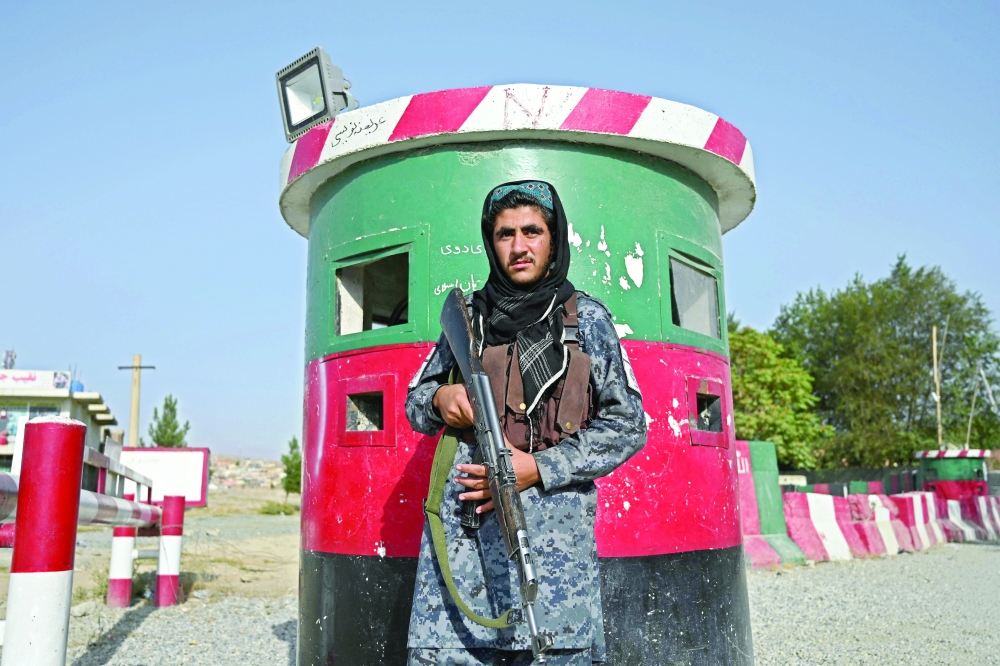 A Taliban fighter working as part of a police force stands guard at the entrance gate of a police district in Kabul. - AFP
