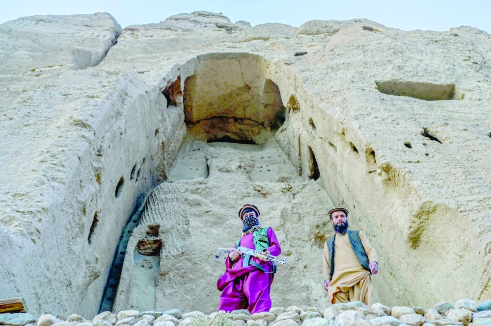 Members of Taliban stand in front of the site where the Shahmama Buddha statue once stood. -- AFP