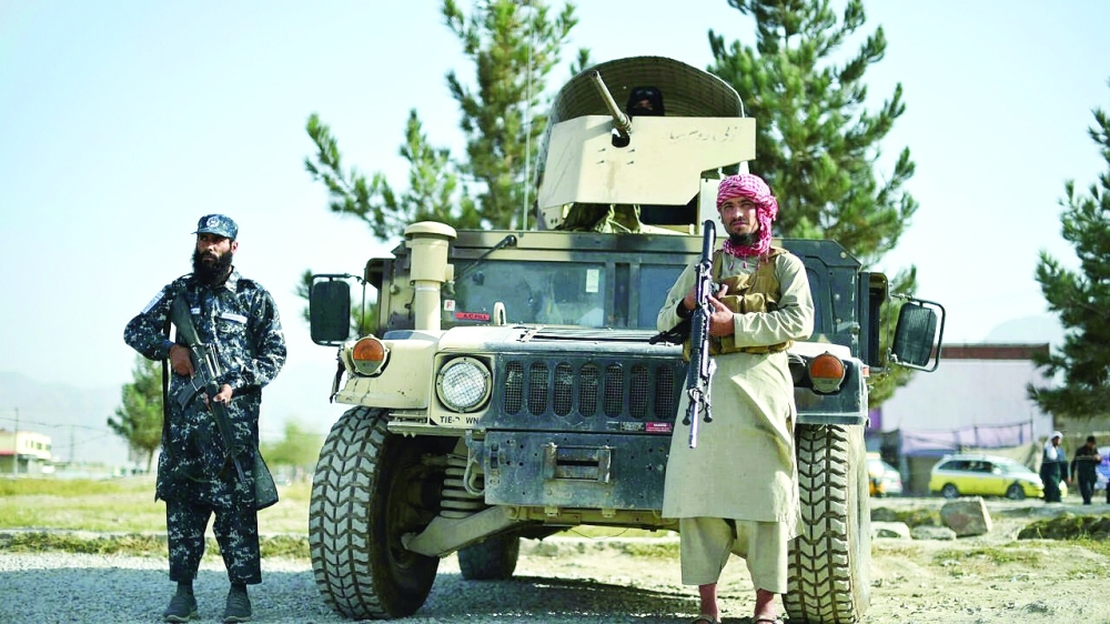 Taliban fighters working as a police force stand guard next to a Humvee vehicle at the entrance gate of a police district in Kabul. -- AFP